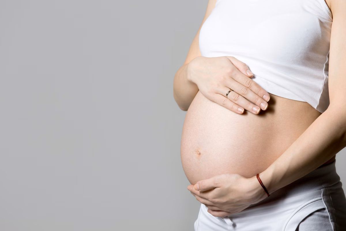 A pregnant belly with hands resting on it